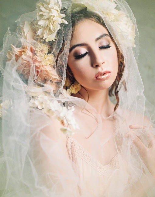 Female model wearing floral headpiece and white veil.